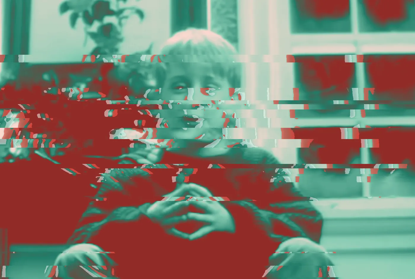 Blond boy in a red sweater with fingers steepled, by a frosty window