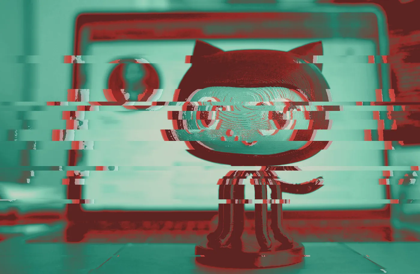 GitHub Octocat figurine standing in front of a blurred laptop screen