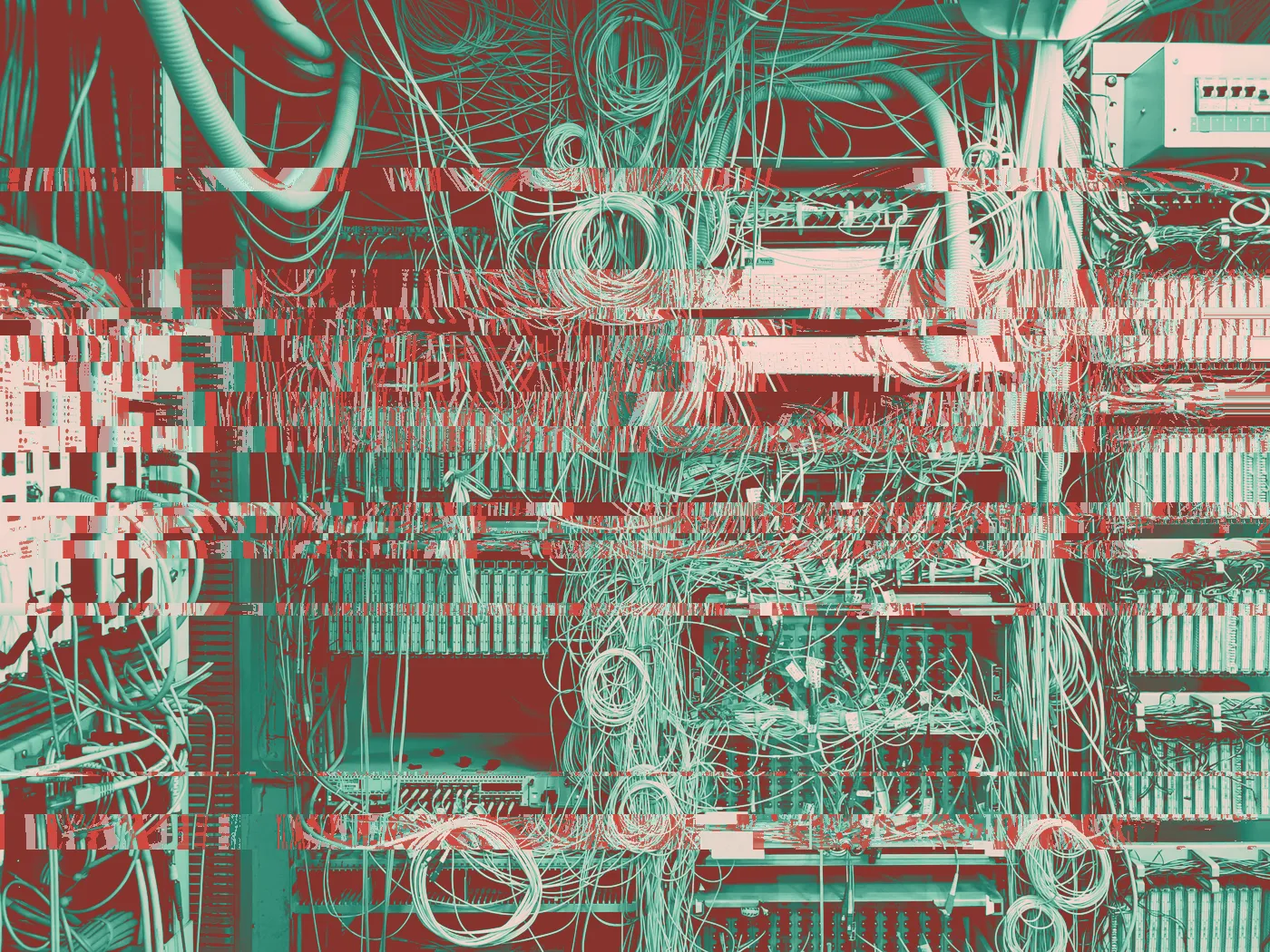 Black and white view of a telecom cabinet overflowing with tangled wires