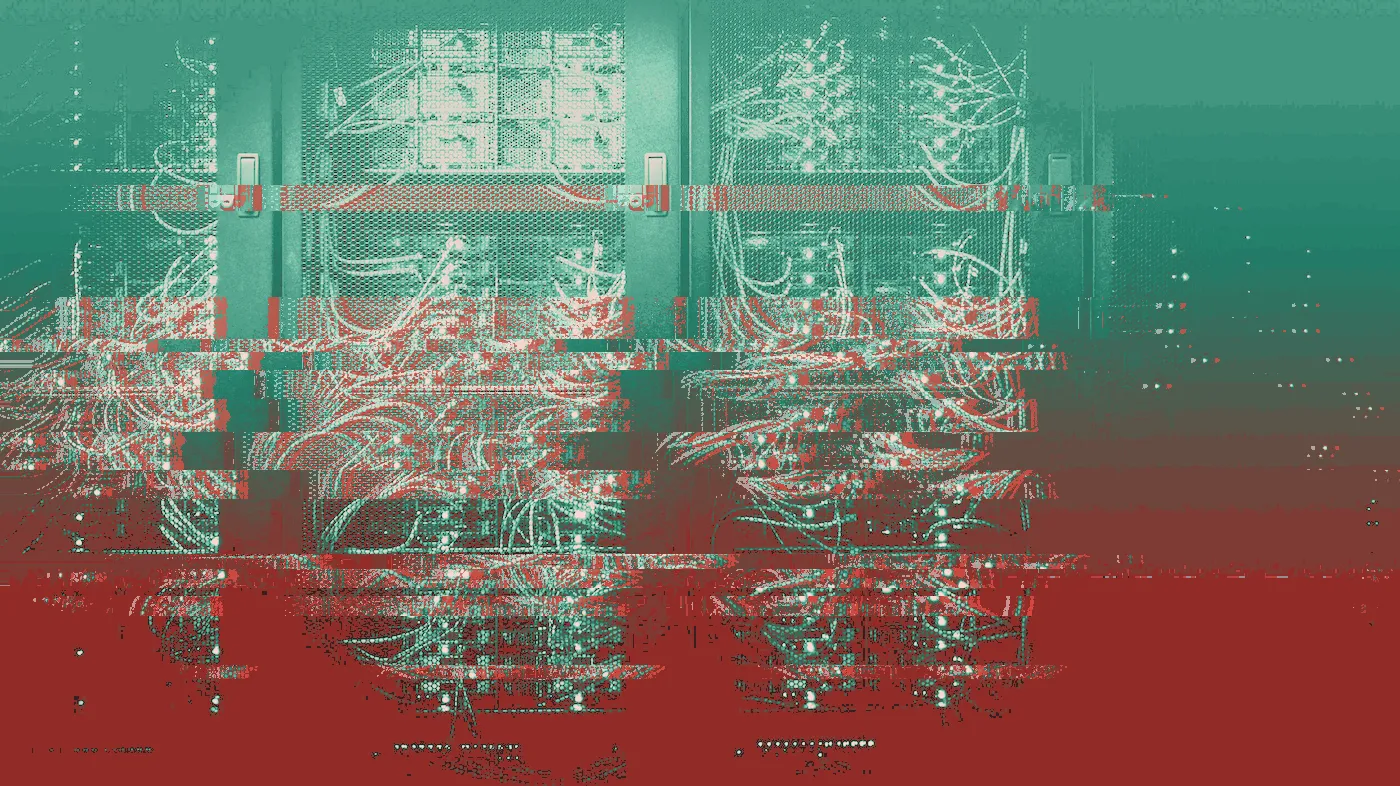 Server racks in a dark data centre, tangled orange and teal cables and green lights