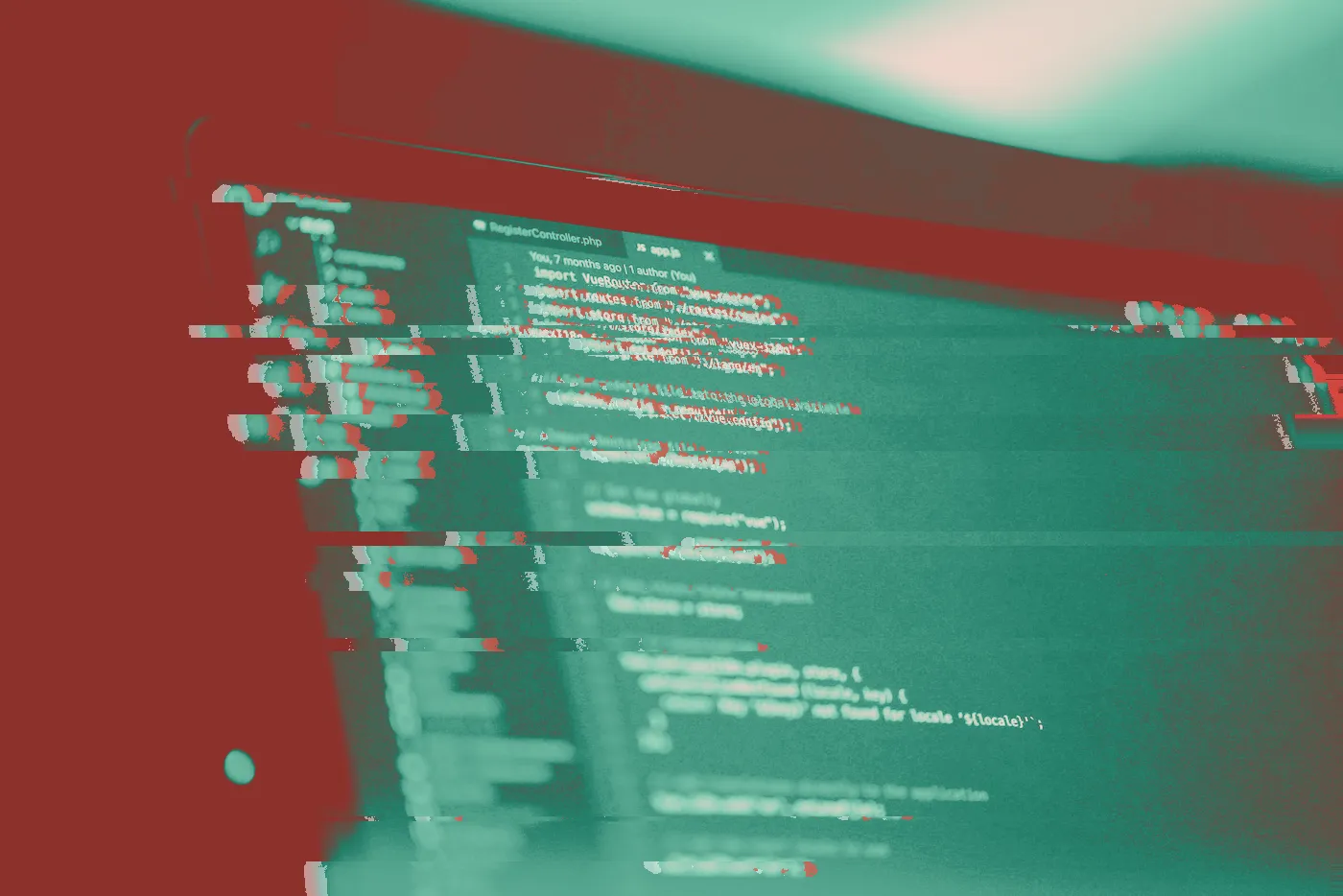 Laptop screen showing colourful source code in a dark editor under purple light
