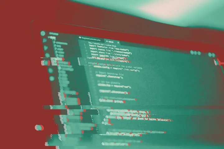 Laptop screen showing colourful source code in a dark editor under purple light