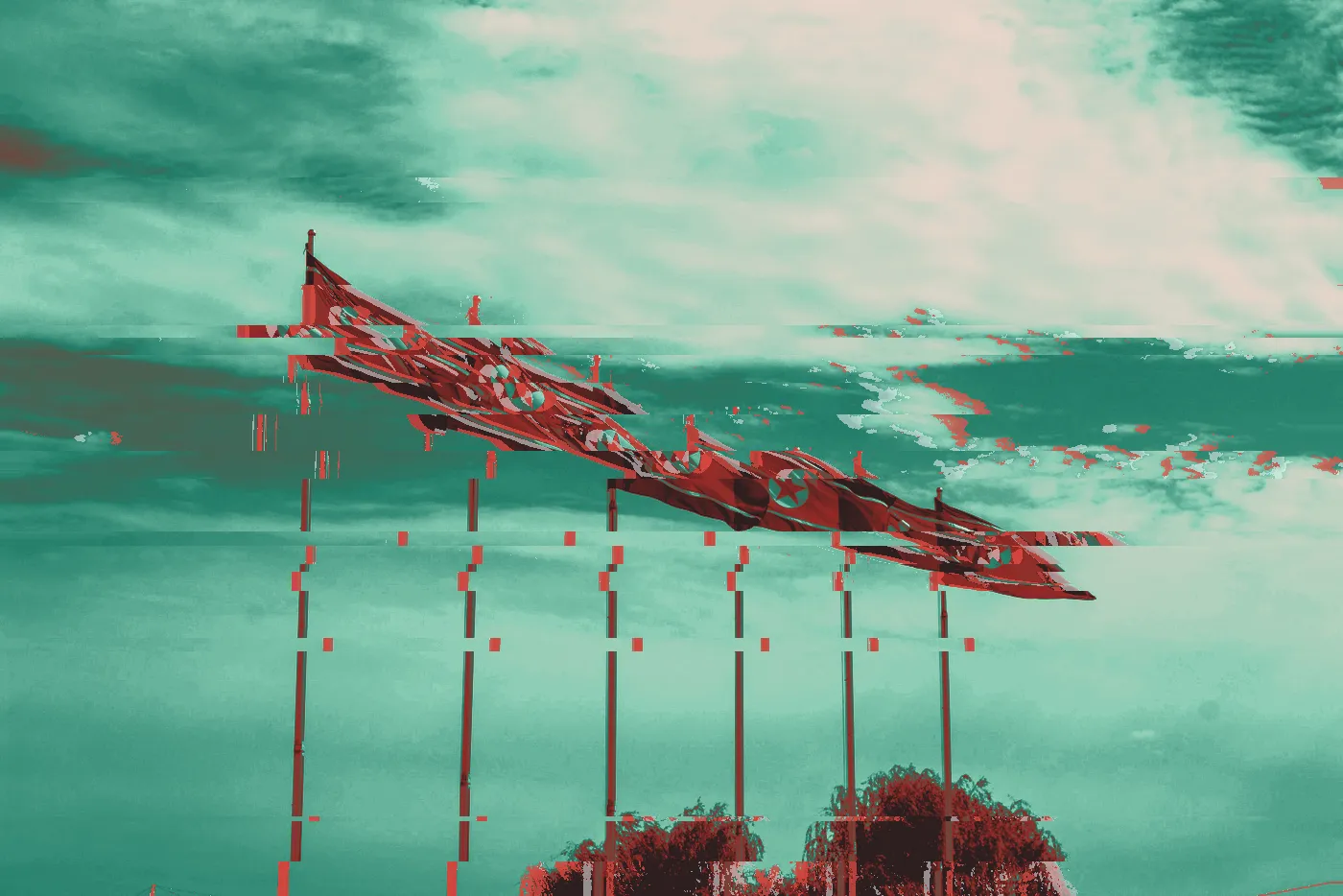 Row of North Korean flags flying on tall poles under a cloudy sky