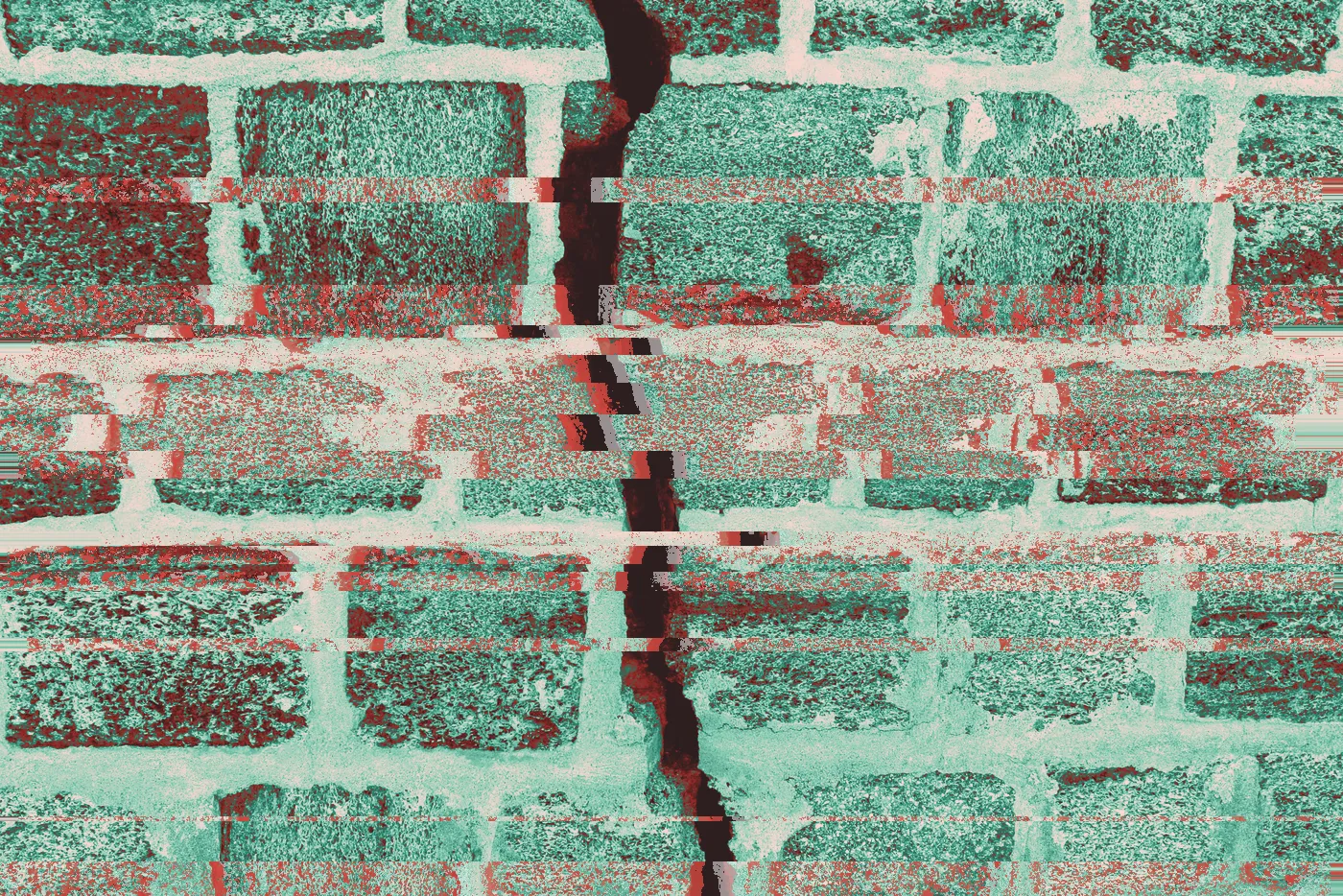 Deep crack running down a weathered stone block wall