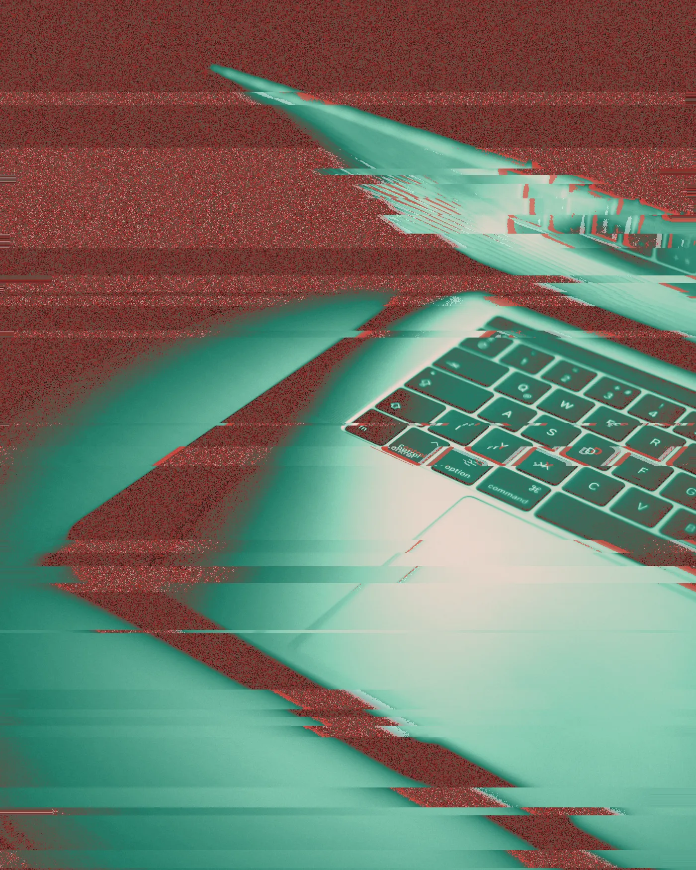 Half-open MacBook with its keyboard glowing orange and purple in the dark