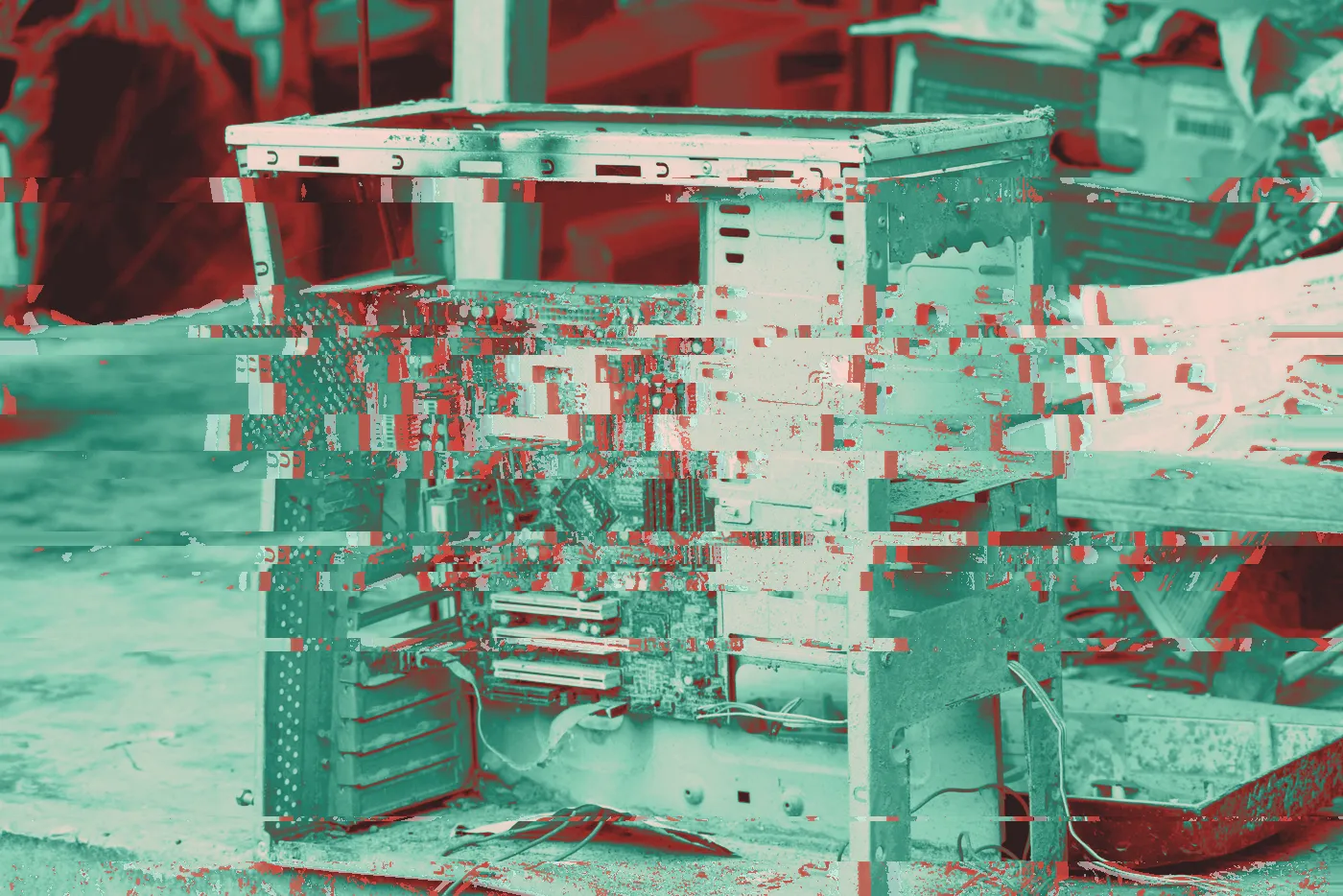 Gutted desktop computer case with a mud-caked motherboard among debris and newspapers